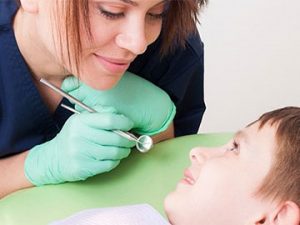 dental professional shows tools to young patient