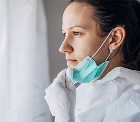 medical professional looking out window wearing protective gear