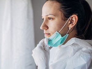 medical professional looking out window wearing protective gear