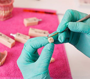 hands fixing tooth in lab