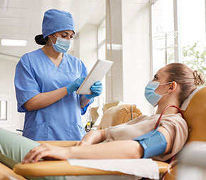 woman taking stats from woman about to give blood