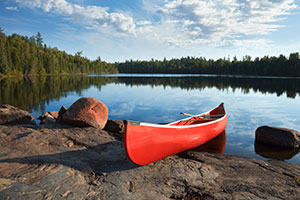 red canoe on shore of lake