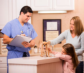 vet tech weighs new puppy as family looks on