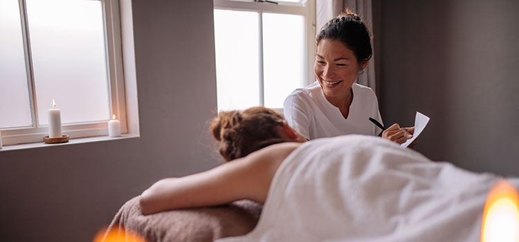female massage therapist talking with client on massage table