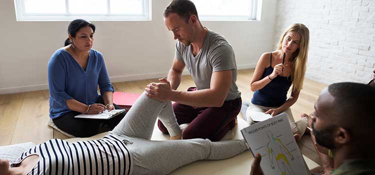 male masseuse massages patients knee in group session