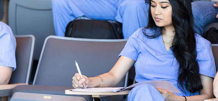 female nursing student takes notes in class