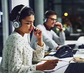 woman taking call and working on transcription at desk