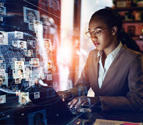 professional on laptop with holograph of faces and lines