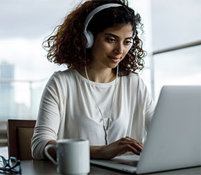 person working at desk with laptop and coffee