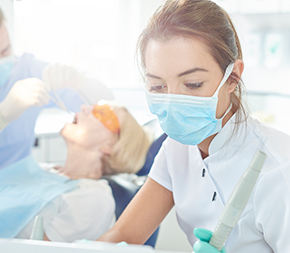 female dental assistant helps dentist