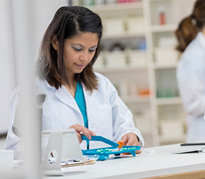 pharmacy technician counts medicine at counter