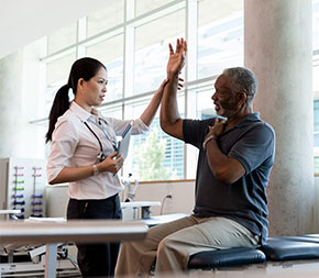 medical professional helps patient move arm above head