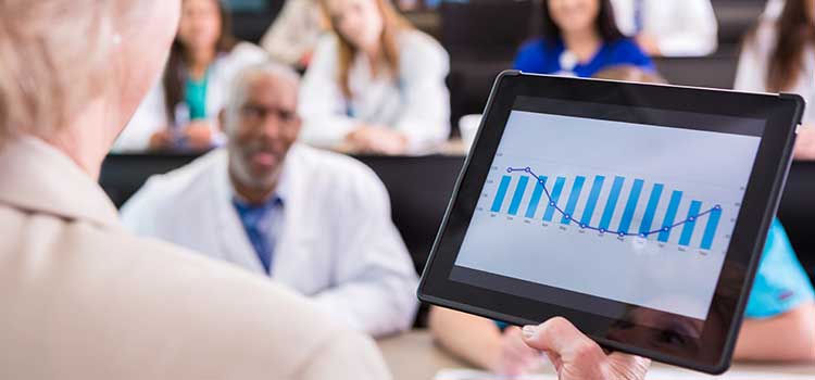 instructor looking at tablet in front of classroom