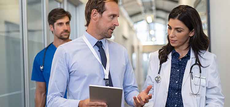 two epidemiologists discussing a case in a hospital hallway