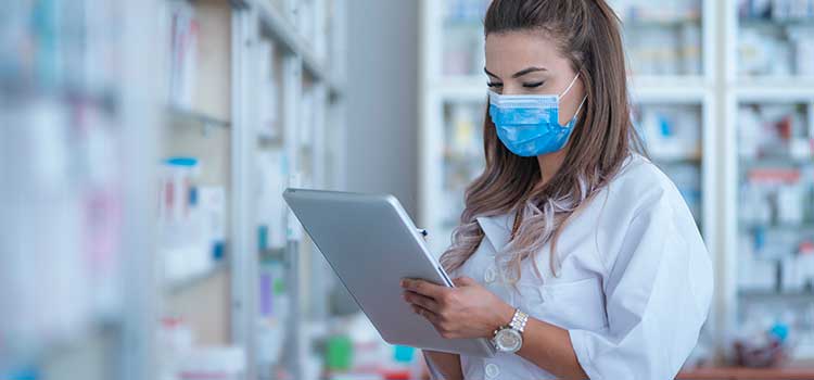 pharmacy technician looking at laptop in pharmacy