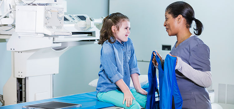 x-ray technician talks to young patient before exam