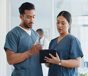 medical assistant consults on patient data on tablet with peer at clinic