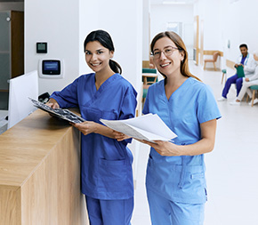two medical assistants stand by nurses station