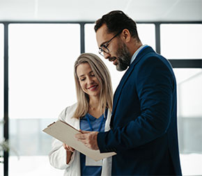 healthcare manager shows a clipboard with information to a doctor