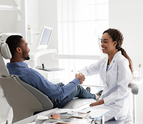 alabama dental assistant shakes new patients hand while reviewing dental history