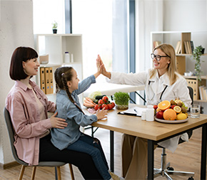 pediatric nutritionist high fives child sitting on mom's lap