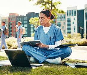 a medical assistant student studies on a campus lawn