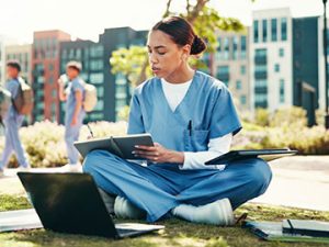 a medical assistant student studies on a campus lawn
