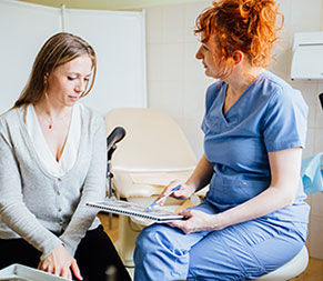 a medical assistant sits down and reviews medical history with a patient