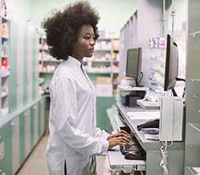 a pharmacy technician uses a computer in a pharmacy lab