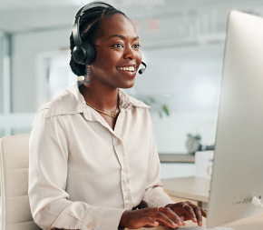 African American women smiling while talking on phone headset and computer
